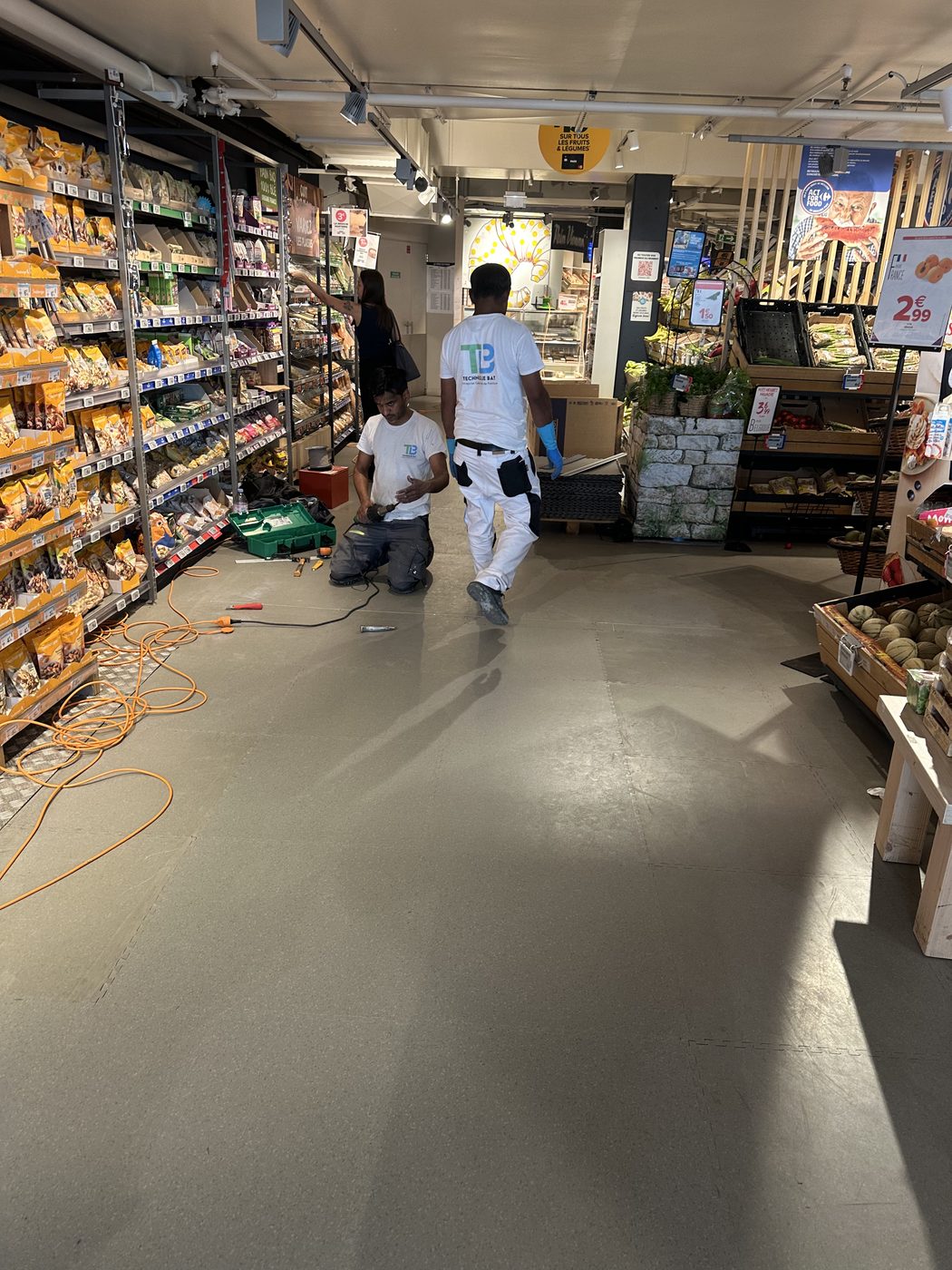 Compagnons posant des dalles de sol dans un rayon de supermarché ouvert